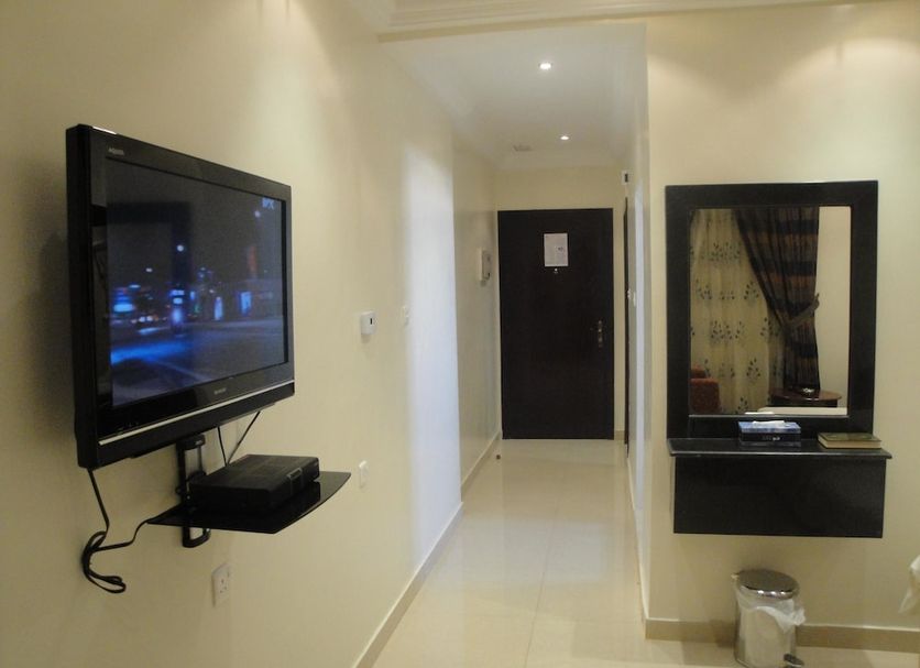 Marina Royal Hotel Suite in Kuwait City hallway with wall-mounted TV, desk mirror, and door