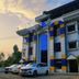 Karthika Residency in Munnar with colorful facade and parked cars at sunset