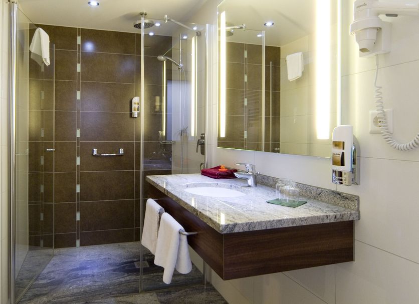 Hotel Sonneck, Schwäbisch Hall bathroom with walk-in shower, vanity, and illuminated mirror