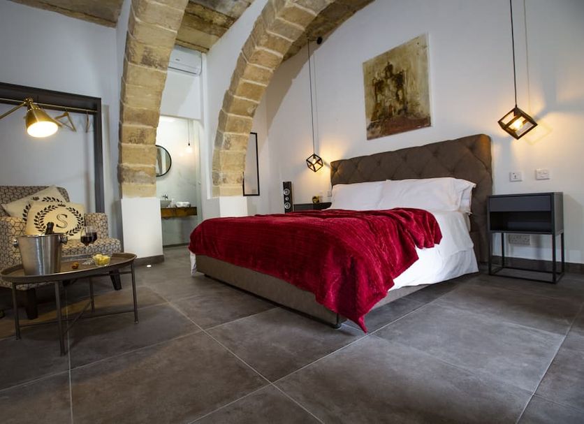 Pjazza Suites Boutique Hotel in Siġġiewi room with stone arches, bed, and seating area