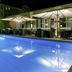 Mercure Hotel Berlin City West in Berlin with a lit outdoor pool and patio dining area at night