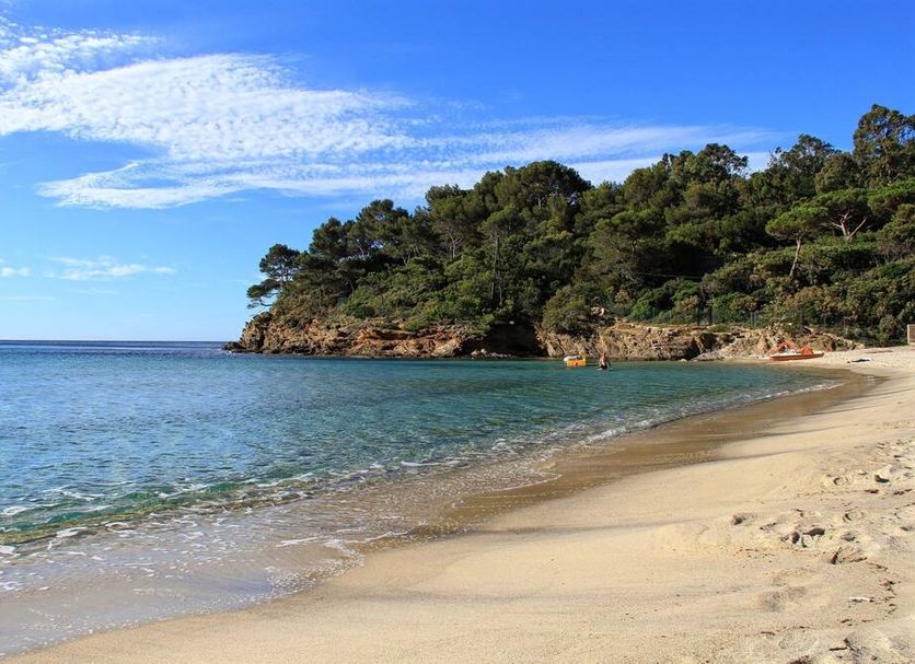Hotel La Voile in Bormes-les-Mimosas with a sandy beach and clear blue sea beside a wooded headland