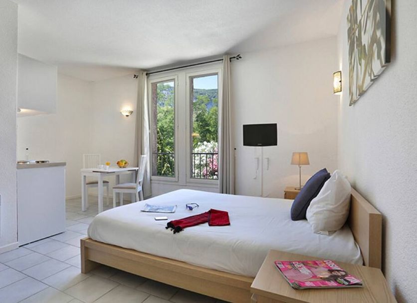Vacancéole - Le Domaine De Chames room with bed, TV, table, and balcony doors in Vallon-Pont-d'Arc