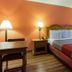 Motel 6 Clarksville Tn room with queen bed, bedside lamps, desk, and orange accent wall in Clarksville