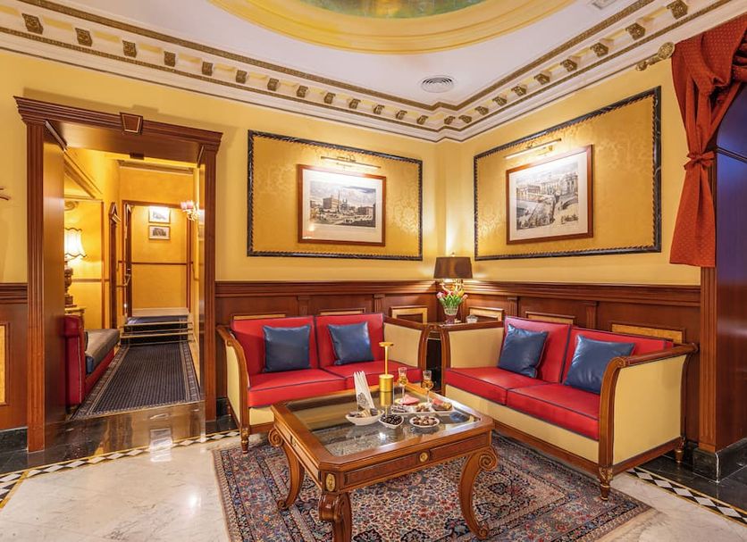Hotel Manfredi Suite In Rome lounge with red sofas, coffee table and ornate gold trim in Rome