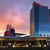 Resorts World Catskills in Monticello at sunset, showing a glass tower and illuminated entrance