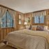 Pine Mountain Club Chalets Resort bedroom with wood-paneled walls, bed, lamps, and windows in Pine Mountain