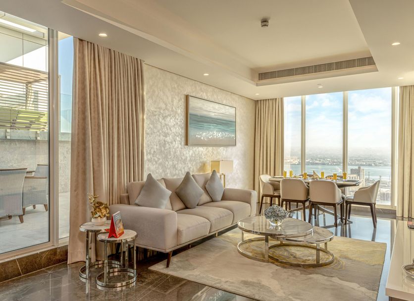 Swiss-Belsuites Admiral Juffair in Manama living room with floor-to-ceiling city view and dining area
