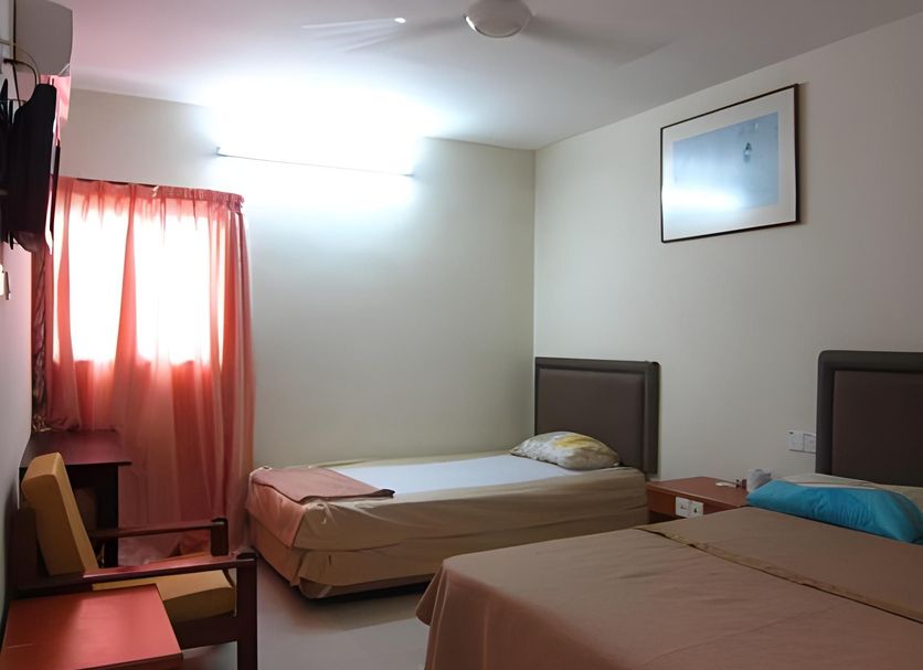 Skudai Baru Hotel in Skudai guest room with two single beds, window curtains, wall art and chair