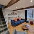 The Lawrence Burnley living room with blue sofa, wood beams, staircase and bay window
