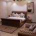 Zifan Hotel & Suites in Karachi guest room with king bed, dresser, patterned rug and armchair