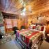 Cottage Inn At Lake Tahoe room in Tahoe City with a wooden interior, stone fireplace, and patterned bedspread