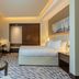 Riviera Rayhaan by Rotana Doha guest room with king bed, desk and city-view window