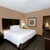 Cobblestone Inn & Suites - Denison room with king bed, lamps, TV, and doorway to another room