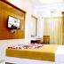 Tr Residency Pondicherry room with bed, wall-mounted TV, desk and curtained window