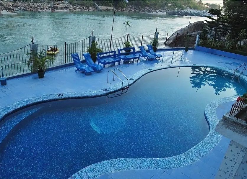 Ganga Beach Resort in Rishikesh with a riverside pool and blue loungers overlooking the water