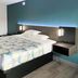 Studio 6 Suites Lafayette guest room with king bed, teal accent wall and bedside lamps in Lafayette.