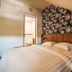 Hotel Frans op den Bult in Deurningen guest room with bed, palm-pattern headboard wall and open bathroom door