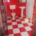 Hotel Sumit Kausani bathroom with red-and-white checkered floor, toilet, pedestal sink and mirror in Kausani