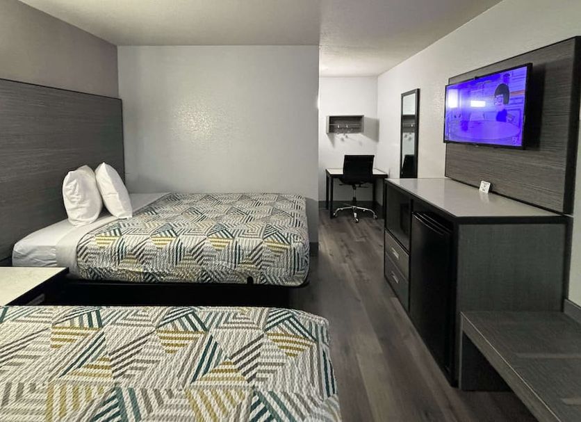 Motel 6 Meridian Ms room with two beds, TV, desk and dark wood furnishings in Meridian