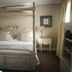 Old House Lodge Beaufort West four-poster bed in a classic guest room with bedside lamps and yellow curtains