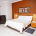Boksburg Boutique Hotel room with double bed, bedside tables, armchair and orange accent wall in Boksburg.