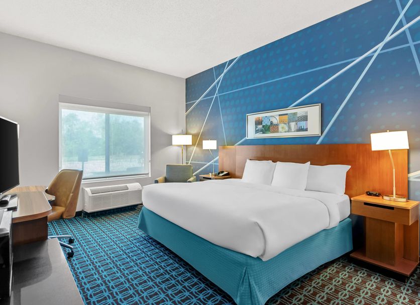 Comfort Inn & Suites Berea guest room with king bed, TV, window seat, desk and blue patterned carpet