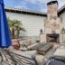 The Tides Laguna Beach outdoor patio with stone fireplace, seating, potted palms and umbrellas