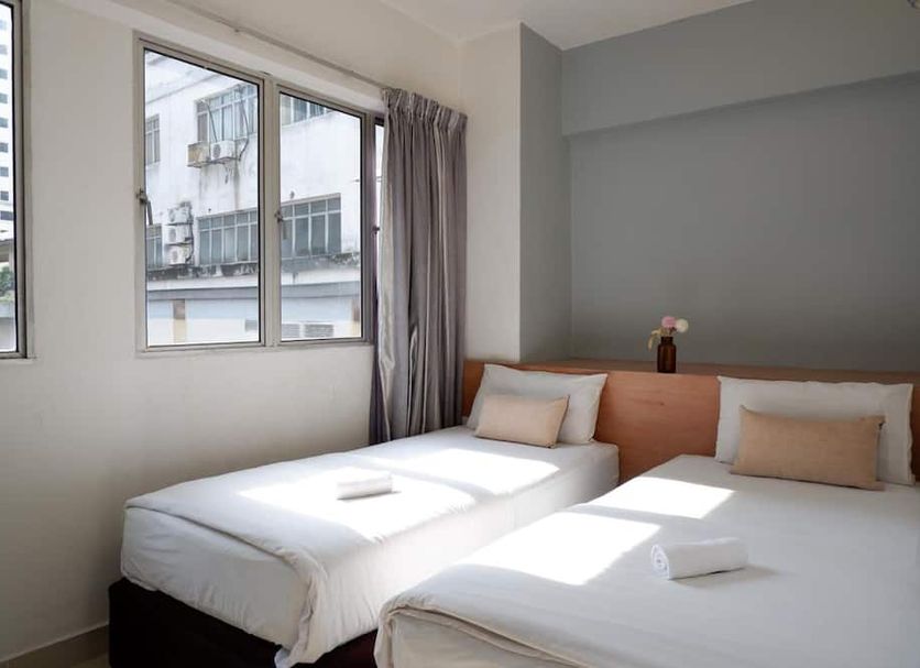 Indah Garden Hotel in Ampang guest room with two twin beds and large windows overlooking nearby buildings.