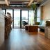 We Come Hostel Taipei City lounge with wood floor, bar stools, sofa, plants and balcony doors