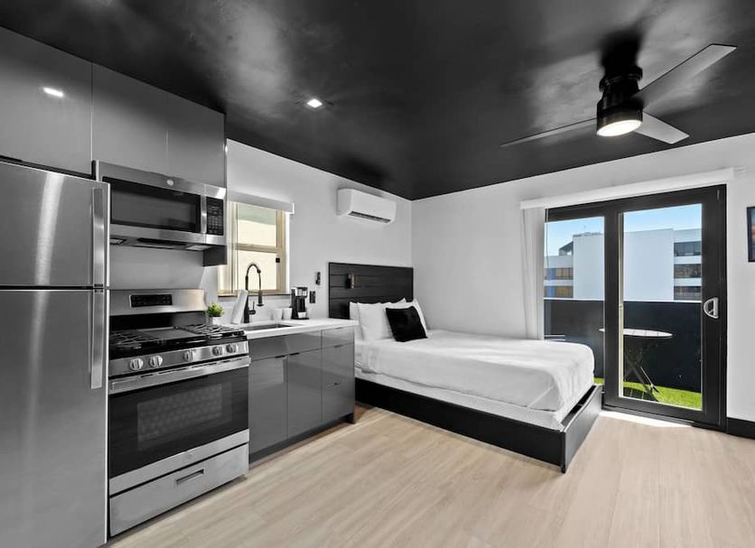 Balboa Park Hotel San Diego studio with kitchenette, bed, and balcony door