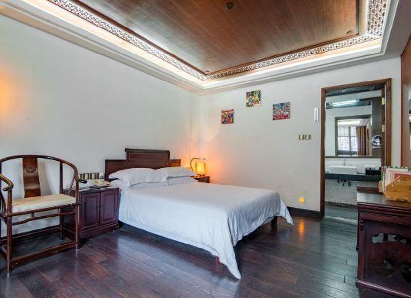 Changle Inn in Yangzhou guest room with bed, dark wood floor, and adjoining bathroom