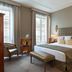 Meliá Paris Vendôme guest room with two beds, tall windows and upholstered headboards in Paris