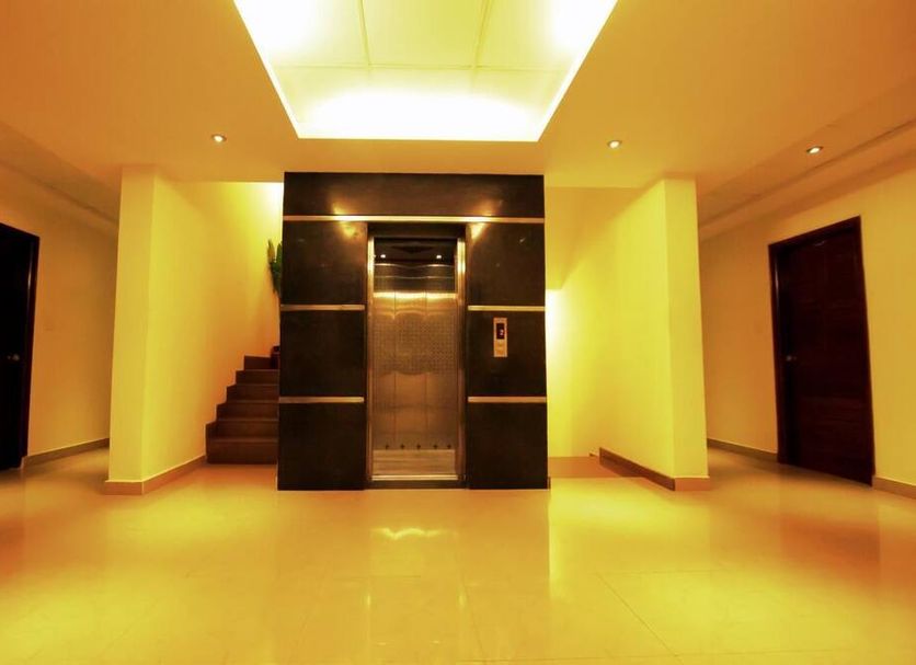 Hotel Sunshine Mysore lobby with central elevator, staircase, and glossy tiled floor