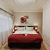Malcolm Lodge Harare guest room with double bed, red throw, and sheer-curtained window
