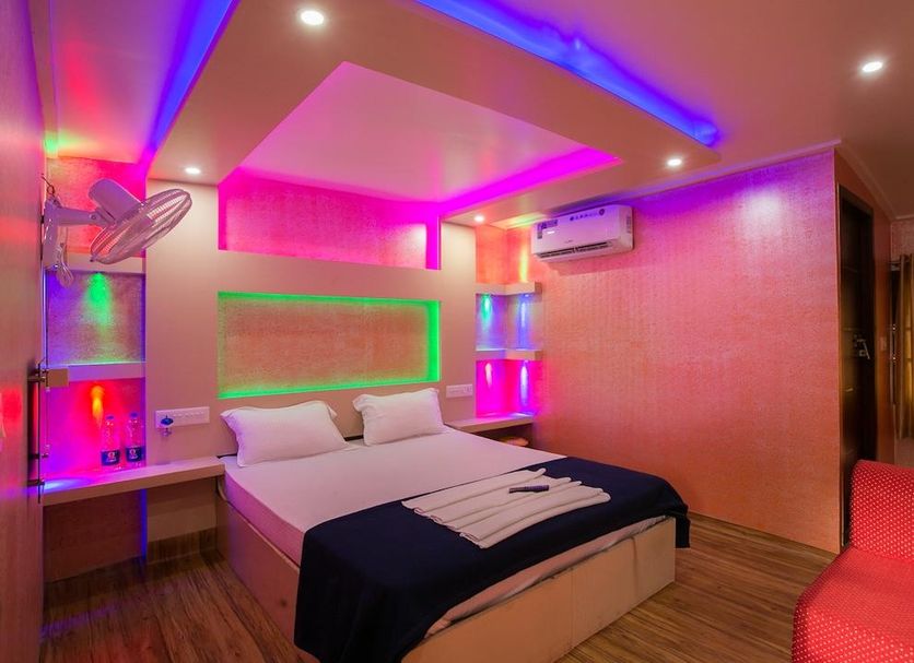 Tharangini Houseboats in Alappuzha, colorful LED-lit bedroom with double bed and red chair