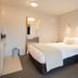 Bella Vista Motel Kaikoura guest room with queen bed, red armchair, and ensuite doorway in Kaikoura