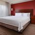Residence Inn by Marriott Dallas Plano/The Colony guest room with king bed, red accent wall, and window light