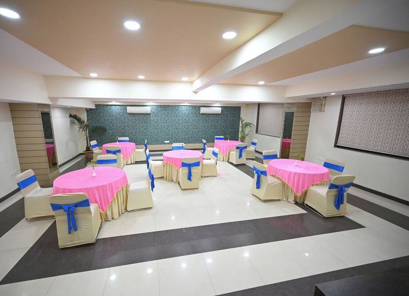 Blueberry Inn Raipur banquet hall with round tables and blue-chair seating