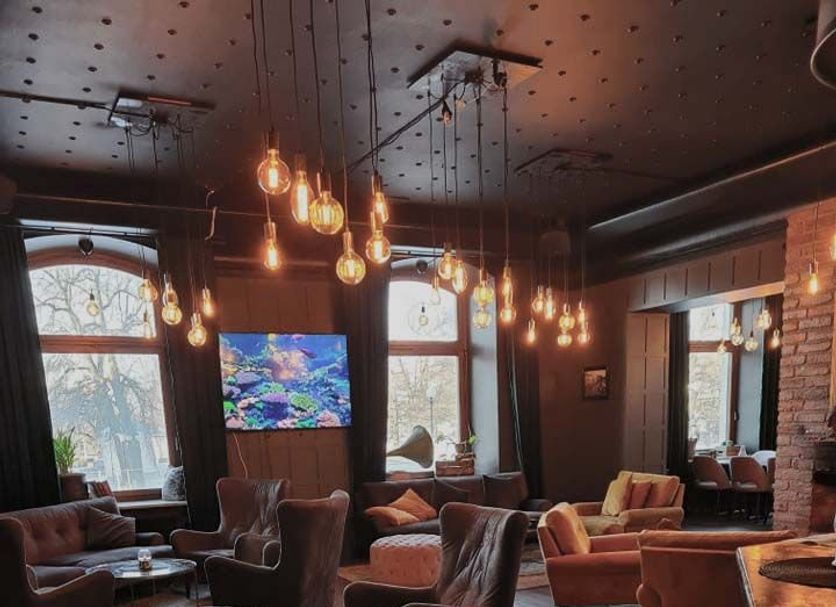 Stadshotellet Kristinehamn lounge with armchairs, hanging pendant lights and TV in Kristinehamn.