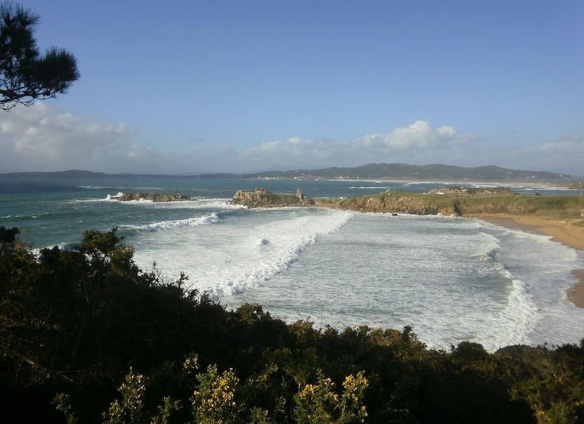 Hotel La Costera in A Lanzada with ocean waves breaking along a sandy bay