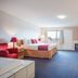Ramada by Wyndham 100 Mile House guest room with two beds, blue carpet, desk, and window view