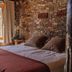 Refugio Del Pintor in Tilcara: rustic guest room with stone wall, wood ceiling, and bed by window