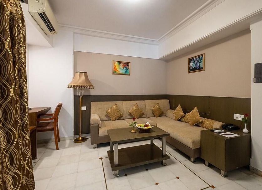 Aditi Vadodara By Wb Hotels in Vadodara, guest room with sectional sofa, coffee table, and floor lamp