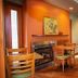 Summers Inn Ludington - Adults Only breakfast area with tables, chairs, fireplace and warm orange wall
