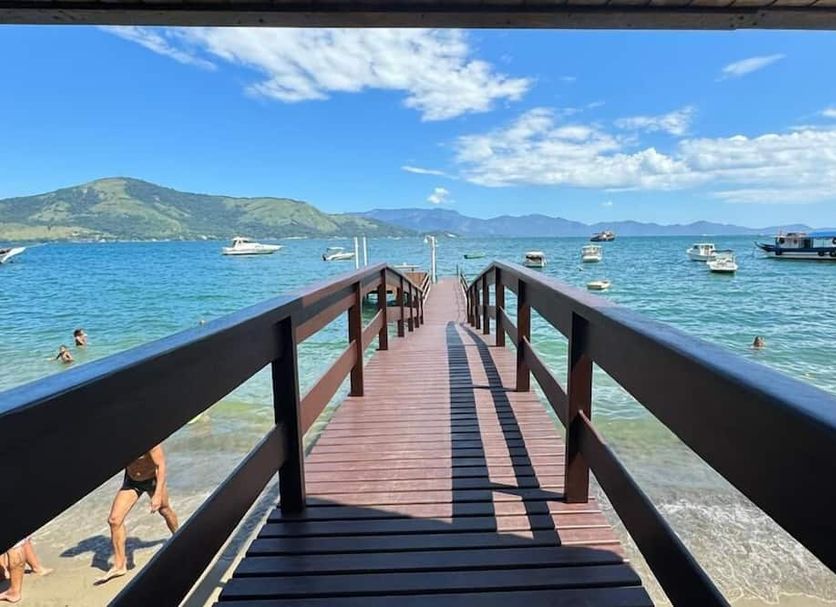 Pousada toca do cambu in Angra dos Reis, wooden pier over clear bay with boats and mountain views