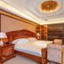White Dolphin Hotel in Qinzhou: ornate suite bedroom with carved wood bed, chandelier and bedside lamps
