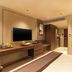 Grand Residency Hotel & Serviced Apartments in Mumbai guest room with wall-mounted TV, desk, bed and bathroom window