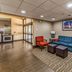 Quality Inn West Plano - Dallas lobby seating area with blue sofa, red chairs, and framed city artwork