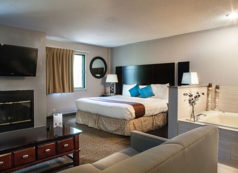 Heartland Inn Coralville guest room with king bed, fireplace, TV, and sofa seating
